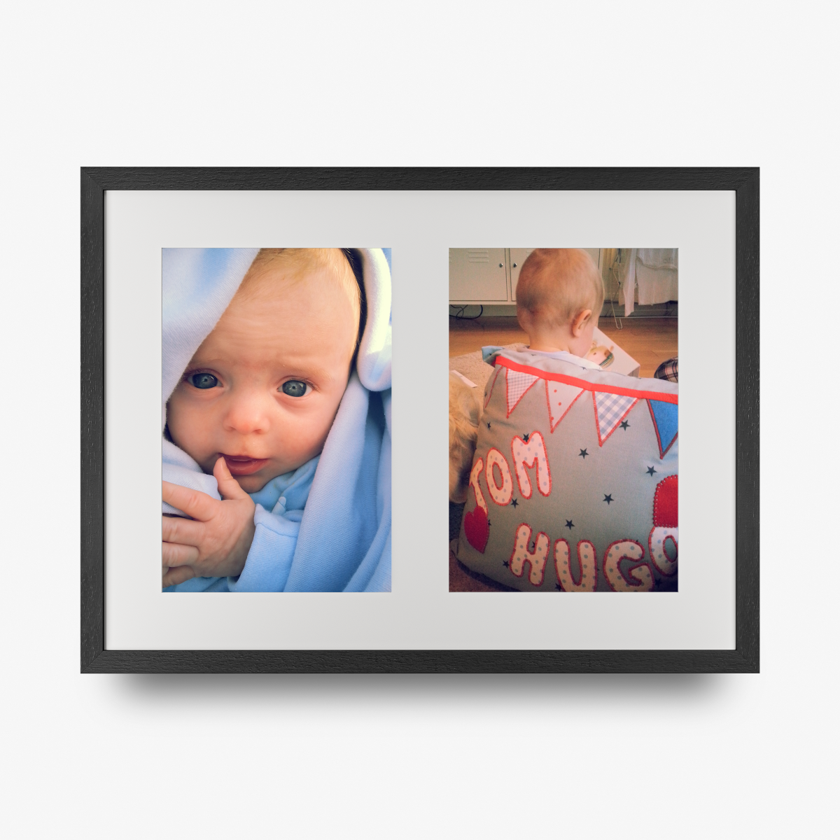 A double aperture multi photo framed print in a black frame featuring a photo of a blue eyed baby and a toddler with his back to the camera. 