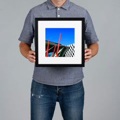A man holds up a 20x20cm black framed photo print. The print features the exterior of The Grand Canal Dock Theatre in Dublin, set in a black frame with a white matt.